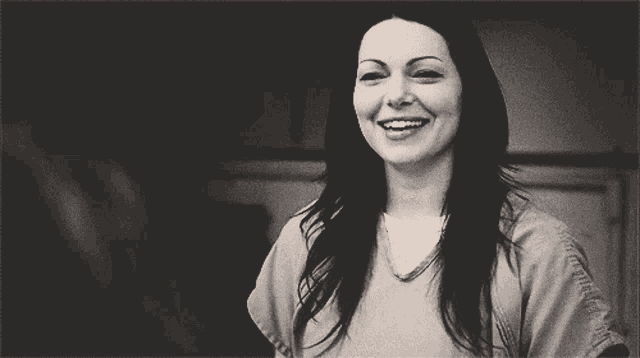 a black and white photo of a woman smiling with her hand in her hair