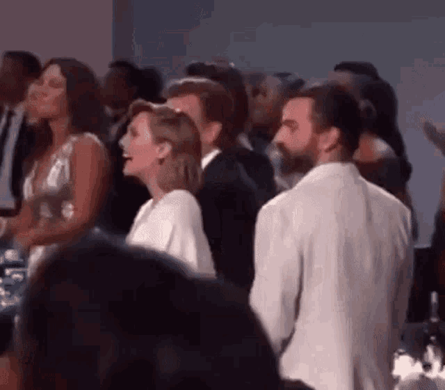 a man and a woman are standing next to each other in a crowd of people at a party .