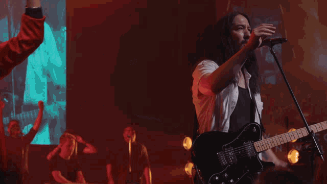 a group of people standing in front of a large screen with a picture of a man playing a guitar