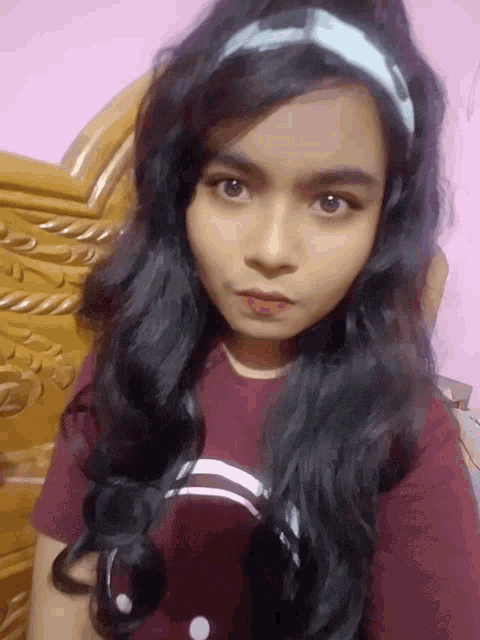 a girl with long black hair is wearing a headband and a red shirt
