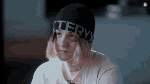 a woman wearing a black beanie and a white shirt is looking at the camera .