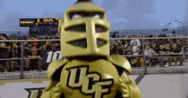 a mascot for ucf stands in front of a scoreboard