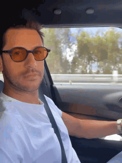 a man wearing sunglasses and a white shirt is sitting in a car