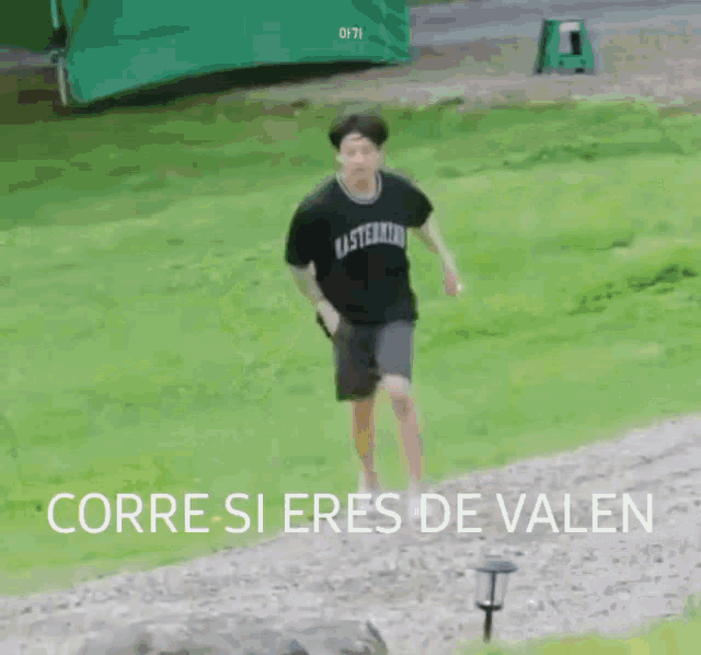 a man in a black shirt and shorts is running on a grassy field .