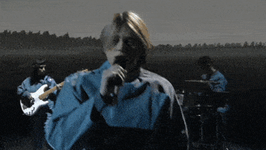 a man is singing into a microphone while another man plays a guitar