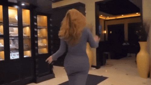a woman in a grey dress is dancing in a room with displays