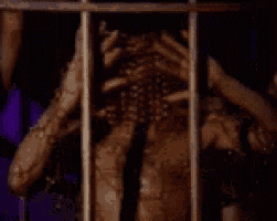 a spider is behind bars in a cage with its mouth open .