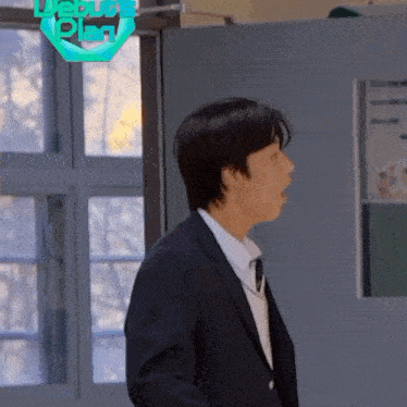 a man in a suit and tie is standing in front of a door with the words debut plan on it .