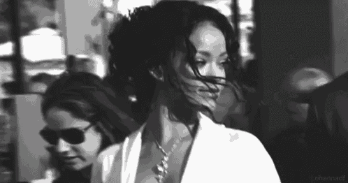 a black and white photo of a woman wearing sunglasses and a white shirt .