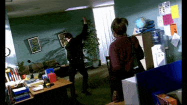 a man and a woman are standing in a room with a water cooler and a globe on the wall