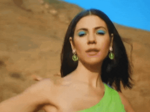 a close up of a woman wearing a green dress and blue eye shadow .