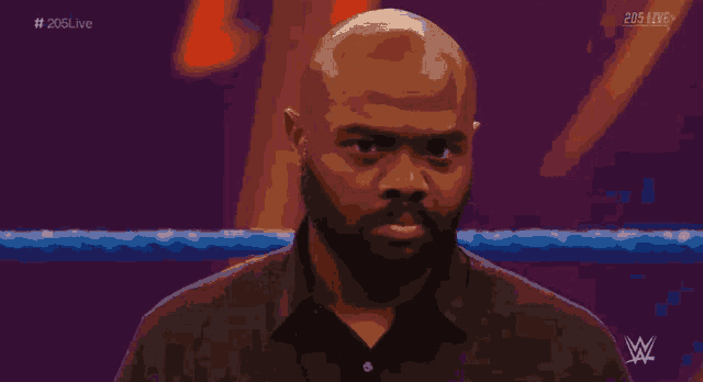 a man stands in front of a wrestling ring with 205 live written on the bottom