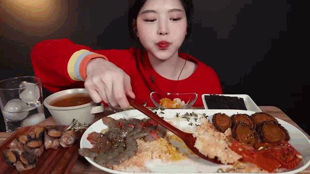 a woman in a red sweater is eating a plate of food