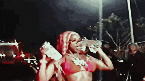 a woman in a red bikini is drinking water from a bottle while standing on a stage .