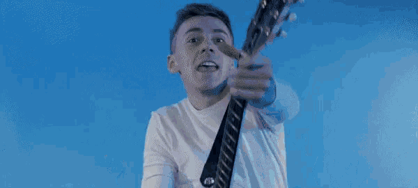 a man in a black shirt is playing a white guitar