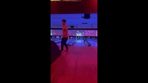 a bowling alley with a large screen behind the bowling pins