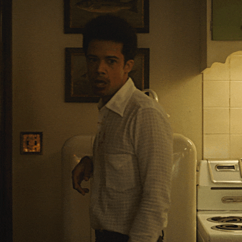 a man in a white shirt stands in front of a stove with a sticker on it that says ' stove '