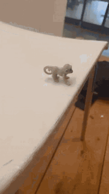 a small toy chameleon is sitting on a white table