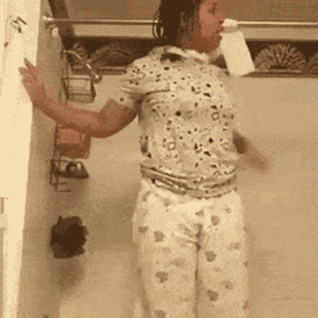 a woman in pajamas is standing in a bathroom with her arms outstretched