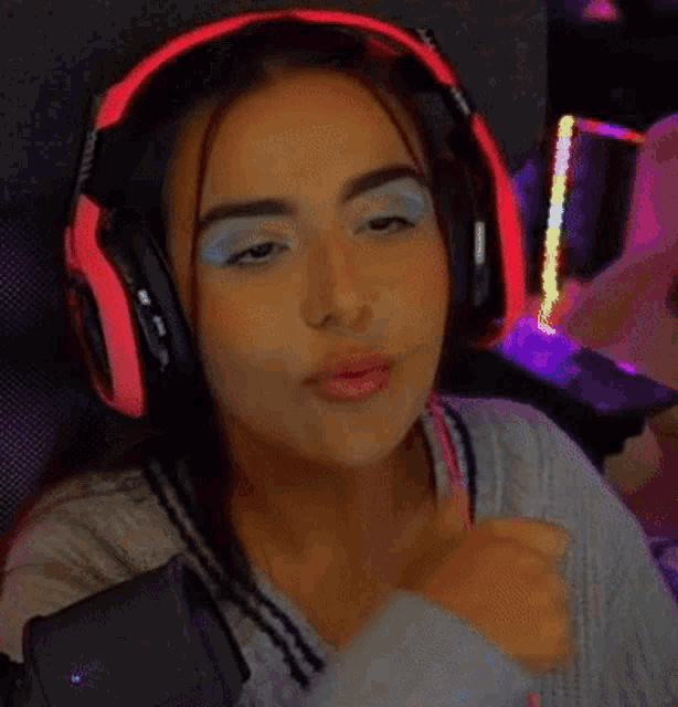 a woman wearing headphones is giving a thumbs up sign while playing a video game .