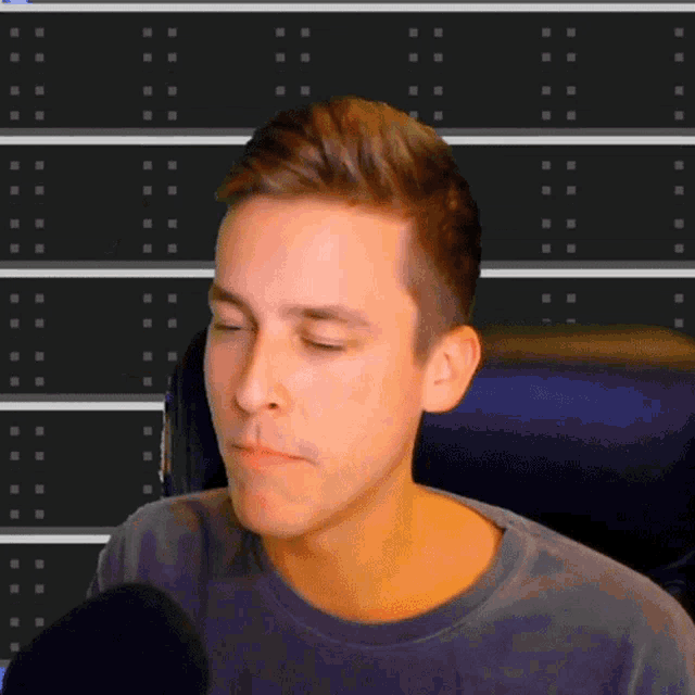 a man sitting in front of a microphone making a funny face