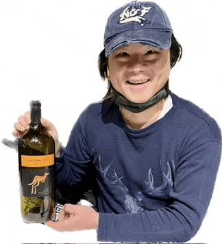 a man wearing a hat that says reef holds a bottle of wine