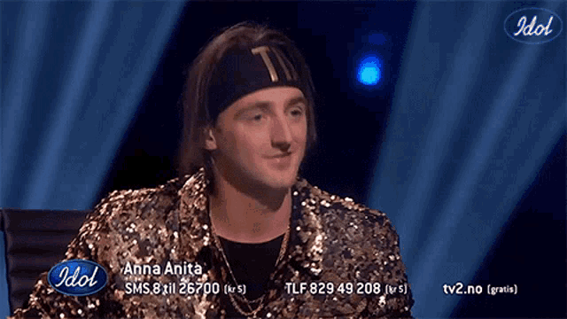 a man in a sequined jacket is on a tv screen with idol written on the bottom
