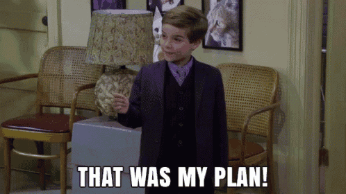 a young boy in a suit stands in a waiting room with the words that was my plan behind him