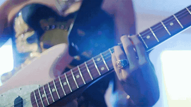 a close up of a person playing a guitar with a ring on their finger