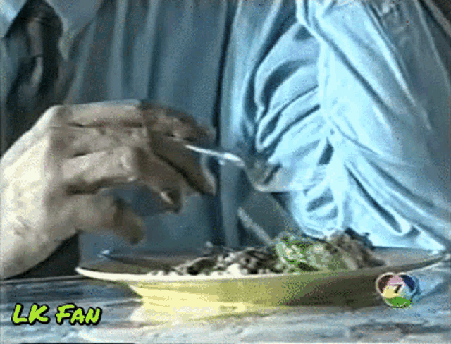 a man is eating a salad with a lk fan watermark on the bottom right