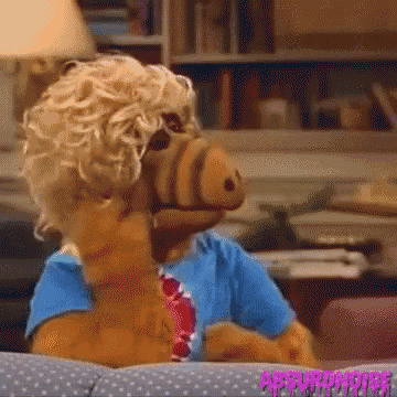 a stuffed animal wearing a blue shirt and tie is sitting on a couch in a room