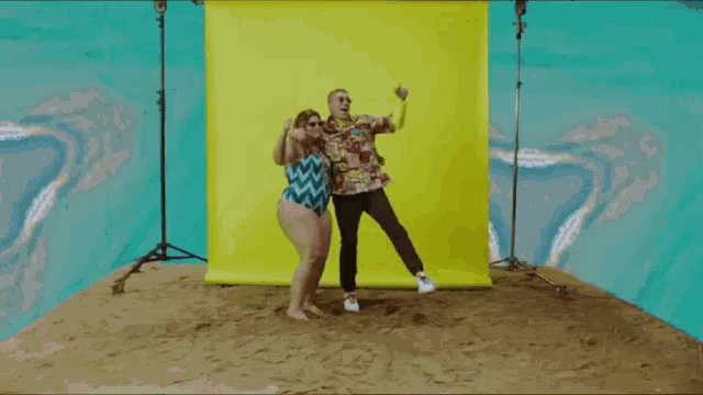 a man and a woman are posing for a picture in front of a yellow backdrop
