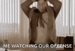 a man in a suit and tie is sitting in front of a window holding his head .