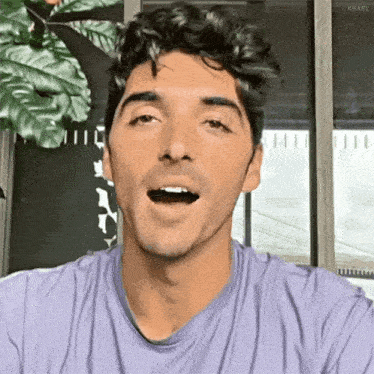 the man is wearing a purple shirt and making a funny face .