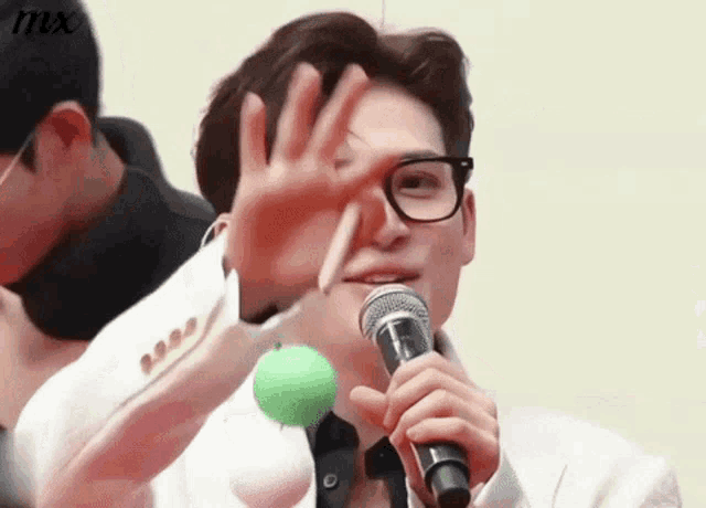 a man with glasses is holding a microphone and making a funny face .