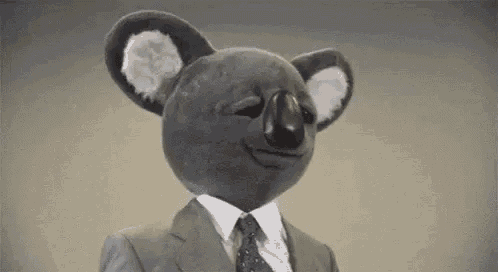 a stuffed koala bear wearing a suit and tie is making a funny face .