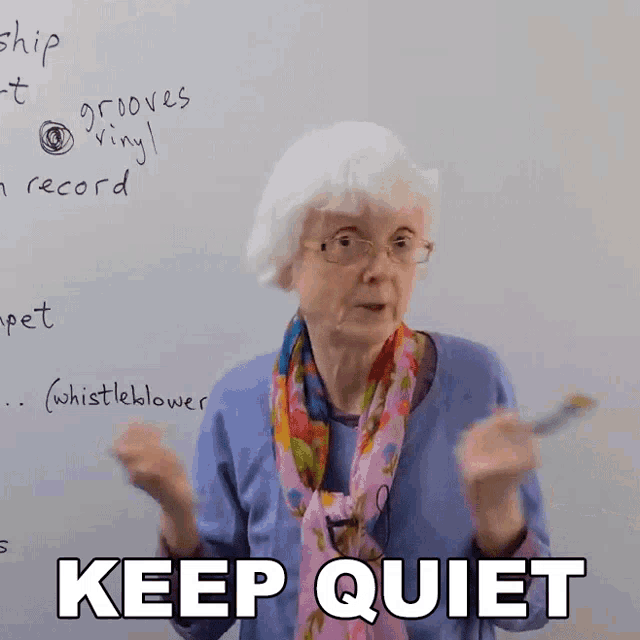 an elderly woman in front of a whiteboard with the words keep quiet written on it