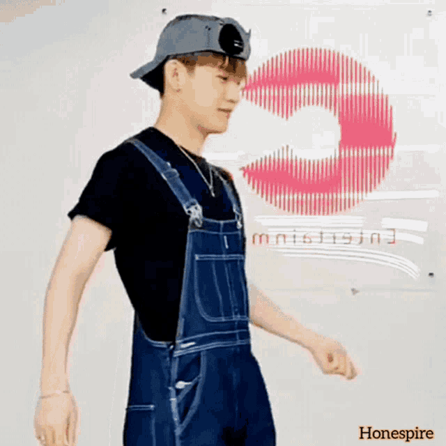 a man wearing overalls and a hat is standing in front of a sign that says honespire on it