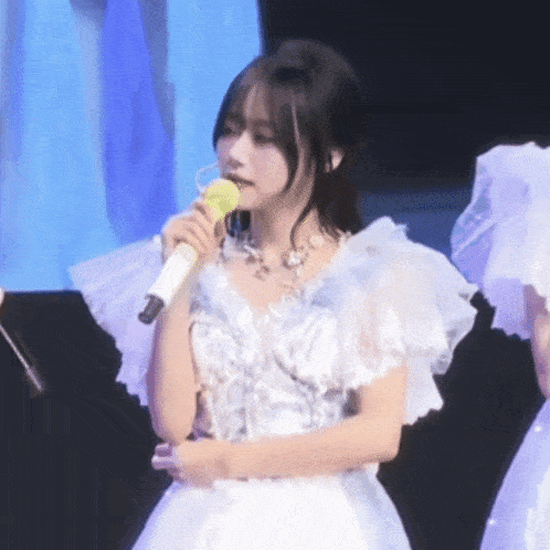 a woman in a white dress holds a microphone in her mouth
