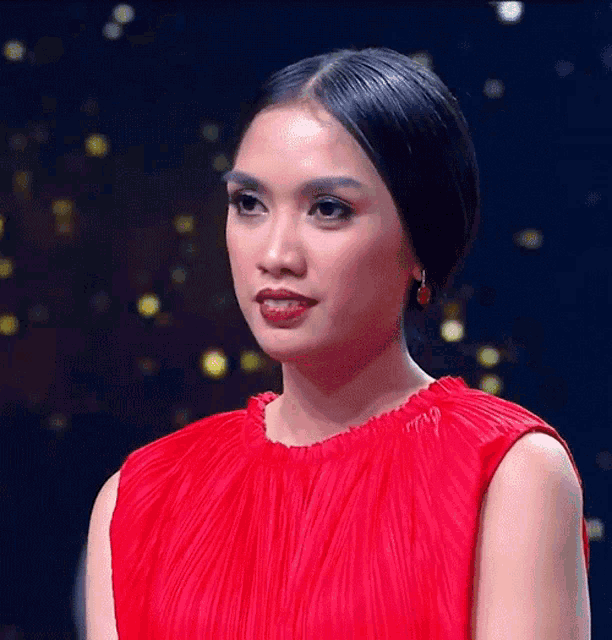 a woman wearing a red dress and earrings is looking at the camera