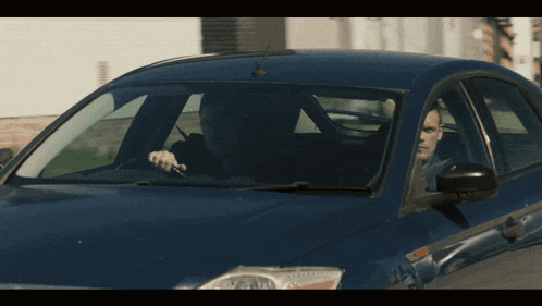 a man is sitting in a blue car with his head out the window