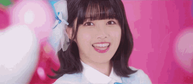 a young girl with short hair is smiling and wearing a blue bow in her hair .