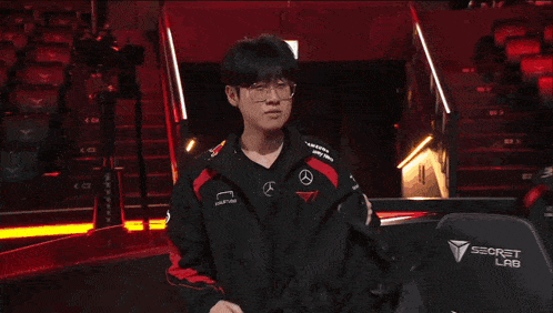 a man wearing glasses and a jacket with a mercedes logo on the sleeve