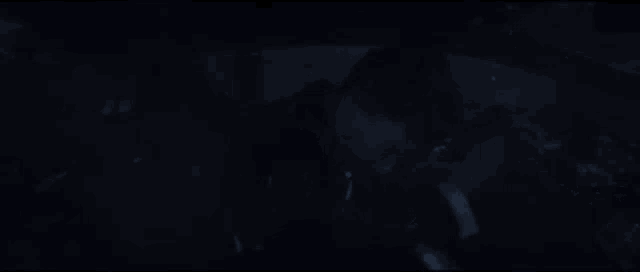 a person is standing in the dark in a dark room with a dark background .