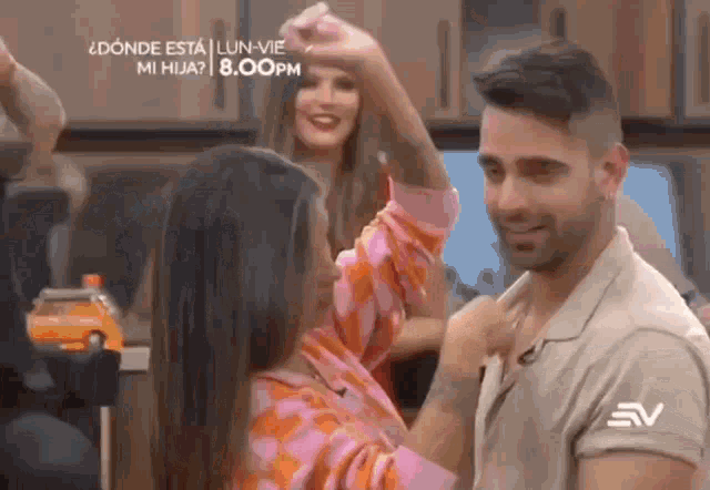 a man and a woman are dancing in a kitchen while a woman holds her arm up in the air .