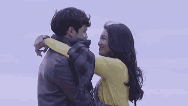 a man and a woman are hugging each other and the woman is wearing a yellow shirt