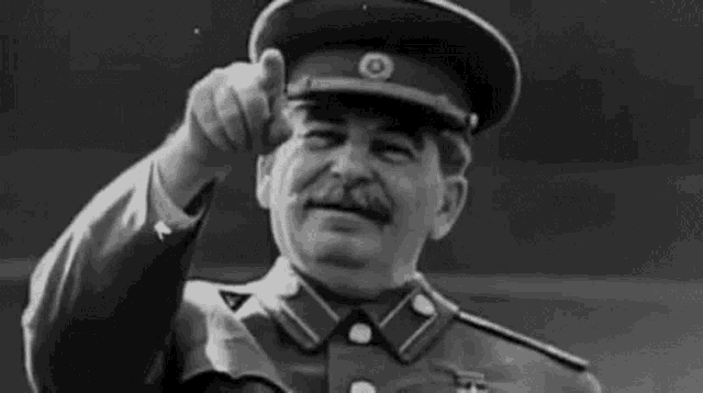 a black and white photo of a man in a military uniform giving a thumbs up sign .