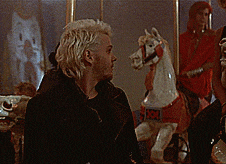 a man in a black jacket stands in front of a horse head puppet