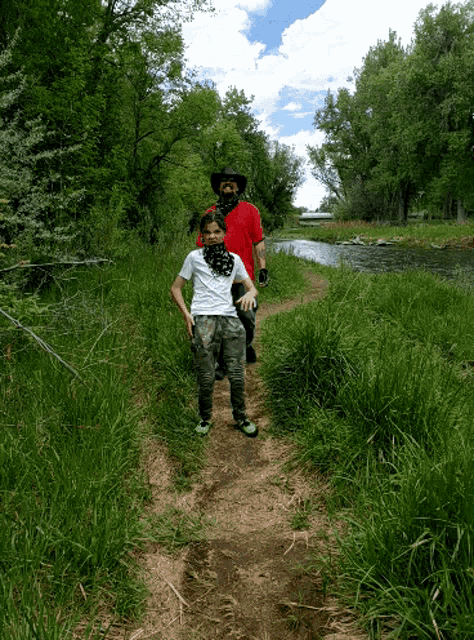 a man and a boy are walking along a dirt path