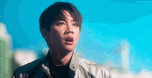 a young man in a leather jacket is looking up at the sky .